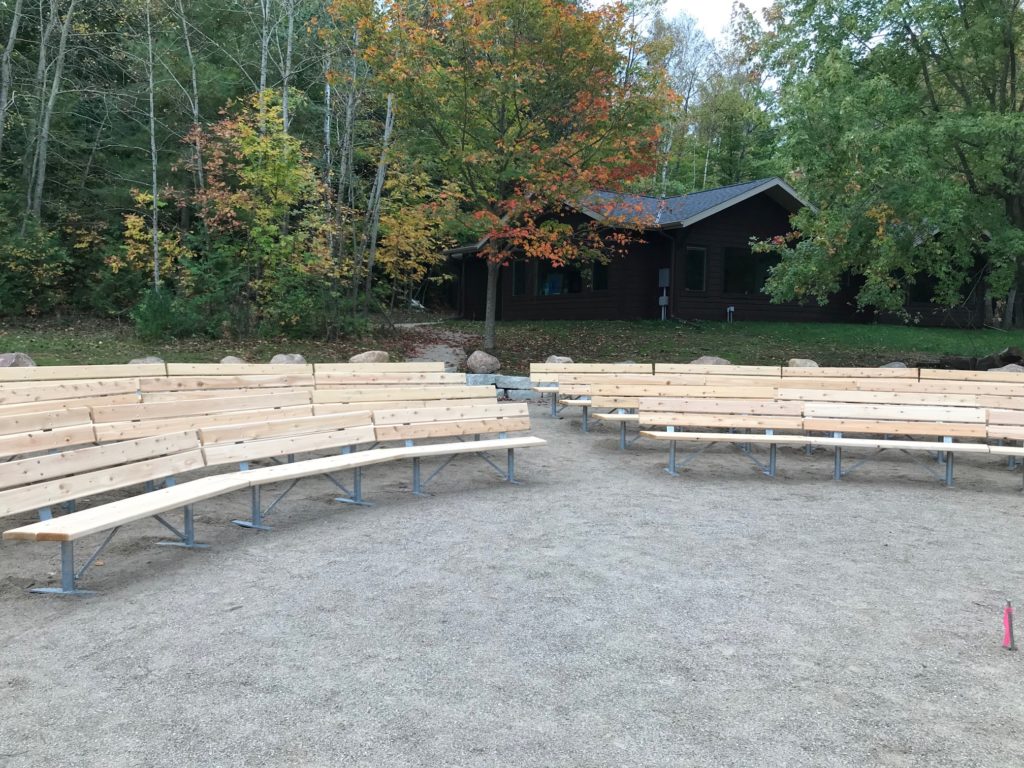 Wooden benches are curved to form an audience at an outdoor amphitheater.